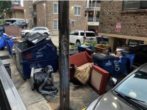 An alleyway scene with a discarded red couch, multiple dumpsters, and other junk awaiting removal by Junkie 4 Jesus Junk Removal in Austin, TX