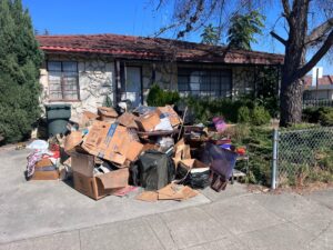 A pile of old furniture and household items on a sidewalk outside an apartment building, for Zero Junk removal in San Jose, CA.