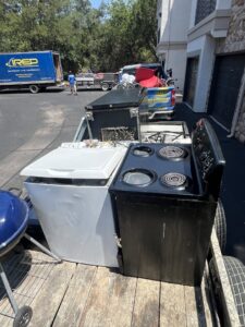 A trailer loaded with old appliances like a washer, stove, and grill, ready for removal by IREP Junk Removal ATX in Austin, TX.