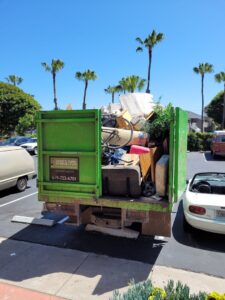 A backyard with broken fence and debris, indicating a cleanup job for Jake's Junk Removal in San Diego, CA.