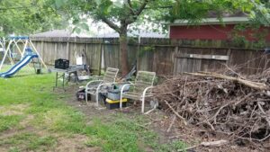 A backyard cluttered with branches, old chairs, and debris, indicating a need for junk removal by Duane's junk removal LLC in Houston, TX.