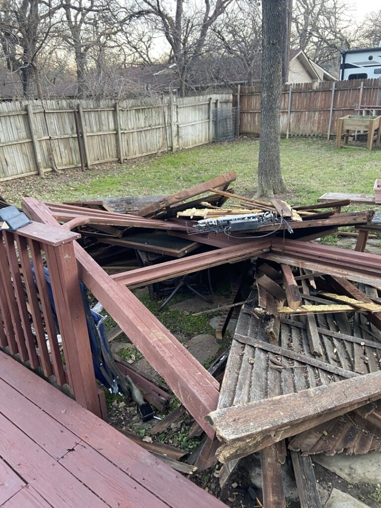 A large pile of broken wood and debris in a backyard, ready for removal by Lolo Hauling Junk Removal in Dallas, TX.