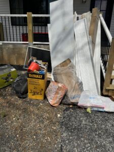 A large pile of household junk and black trash bags in a backyard, ready for removal by High Speed Junk Removal in Levittown, PA.