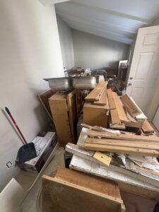 A residential backyard with overgrown grass, trash bags, boxes, and other debris, ready for yard waste removal by Priority Hauling and Junk Removal San Diego.