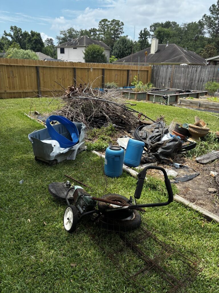 A backyard with a large pile of branches, old equipment, and barrels, ready for yard junk removal by Handymen Junk Removal in Houston, TX.
