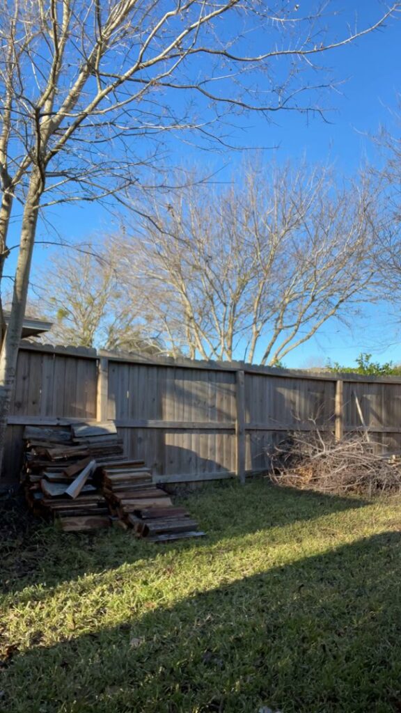 A backyard in Austin, TX, with piles of wood and brush ready for general junk removal by Firefighter Junk Removal.