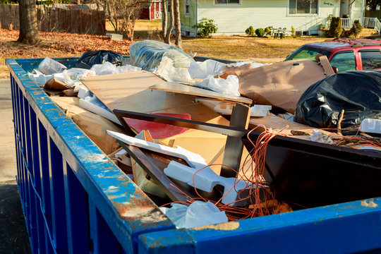 A blue roll-off dumpster filled with construction debris and household junk, ready for pickup by Epic Junk Removal SD in San Diego, CA.