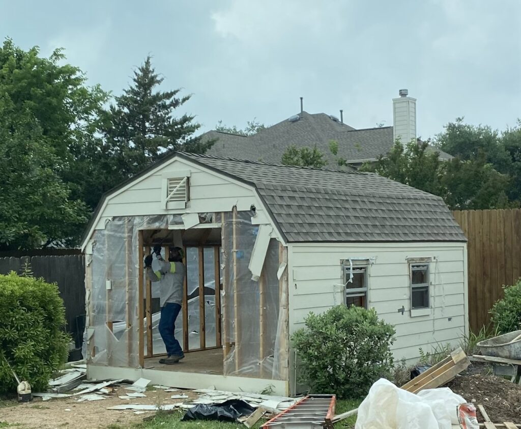 A Bobcat skid-steer loader filling a junk removal trailer with debris for Big Ox Junk Removal in Leander, TX.