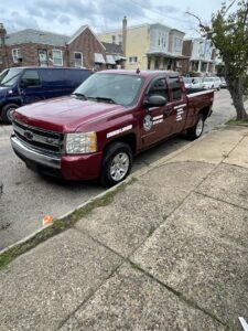 A branded red pickup truck from Kay's Brothers Junk Removal parked on a residential street in Philadelphia, PA.
