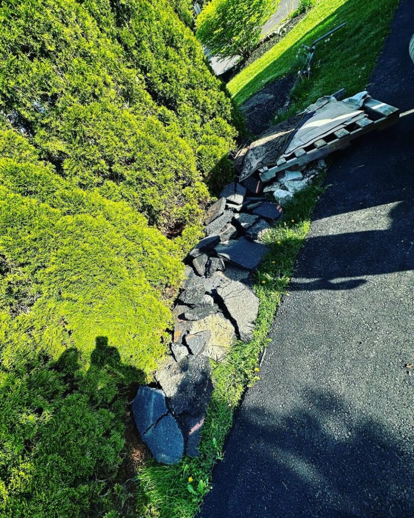Broken asphalt and concrete debris next to bushes, ready for removal by S&M Junk Removal in Philadelphia, PA.