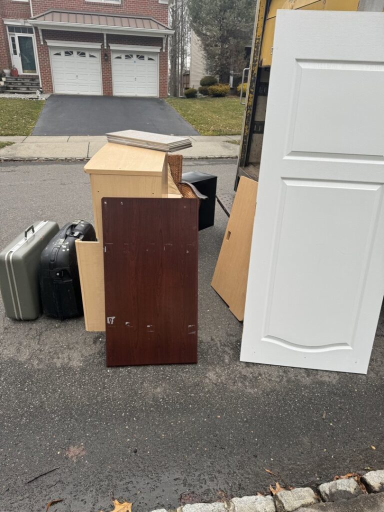 A broken bathtub, drywall sheets, and bags of material outside a house, ready for High Speed Junk Removal in Levittown, PA.