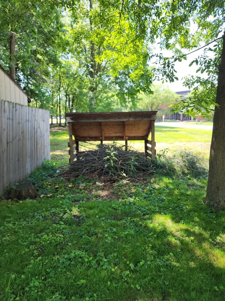 A pile of brush and branches under a wooden structure, ready for yard waste removal by We Haul It Cleaning Service LLC in Canal Winchester, OH.