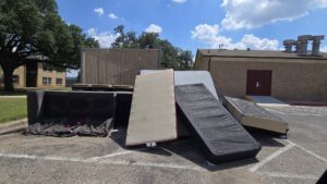 Multiple mattresses and a couch left in a parking lot, requiring bulk junk removal by IREP Junk Removal ATX in Austin, TX.