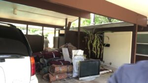A pile of rolled carpets, an old television, and other items under a carport, awaiting junk removal by Jacksonville Hauling & Junk Removal in Jacksonville, FL.