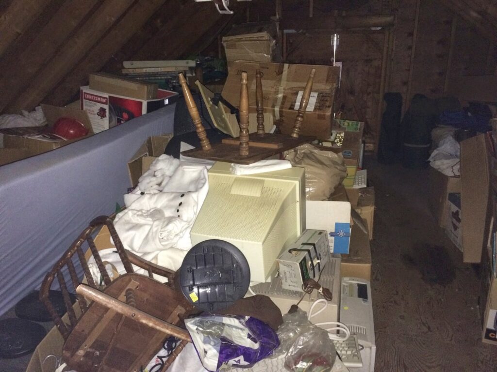 A cluttered attic filled with old furniture, boxes, and electronics ready for junk removal by Capital junk hauling in Austin, TX