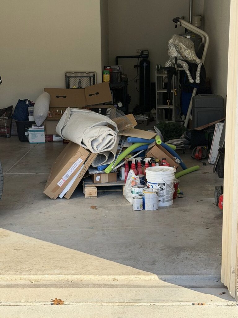 A cluttered garage filled with boxes, paint cans, and various items, ready for junk removal by Faithful Hands Junk Removal in San Antonio, TX.