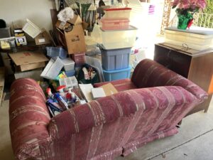 A cluttered garage filled with a sofa, boxes, and various items ready for junk removal by Lug Stars Junk Removal in Columbus, OH.