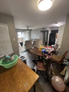 A cluttered living room and kitchen filled with various items, indicating a general junk removal job for IREP Junk Removal ATX in Austin, TX.