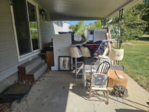 A cluttered residential porch filled with old furniture, boxes, and various items ready for junk removal by Purefoy's Professionals in Columbus, OH.