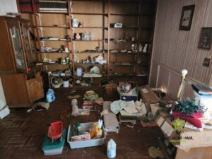 A cluttered room filled with boxes, old furniture, and general junk before cleanout by The Mess Haul in Jacksonville, FL.
