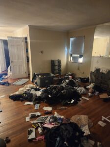 A cluttered room with clothes and various items scattered on the floor, awaiting junk removal by Master Junkers in Powell, OH.