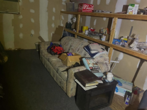 A cluttered room with an old sofa, shelves, and boxes, ready for general junk removal by River City Junk and Debris Removal in Jacksonville, FL.