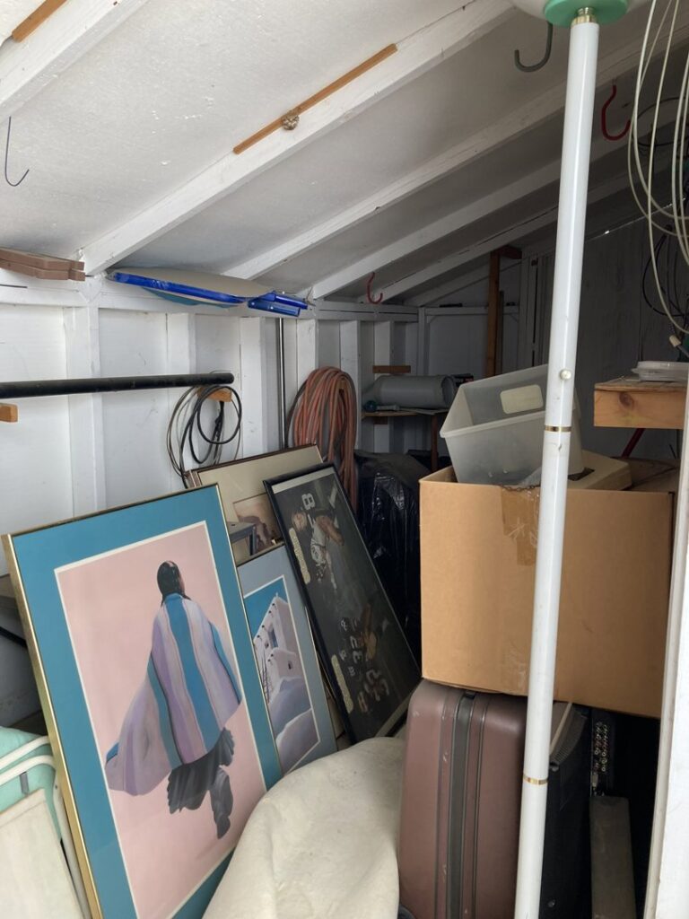 The interior of a cluttered shed filled with framed art, boxes, and miscellaneous items, ready for cleanout by Minutemen Junk Removal in Phoenix, AZ.
