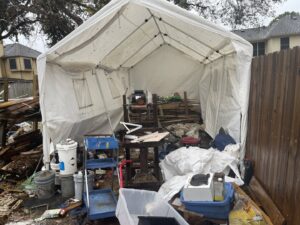 A large white storage tent filled with junk, wood, and debris, indicating a significant junk removal job for Duane's junk removal LLC in Houston, TX.