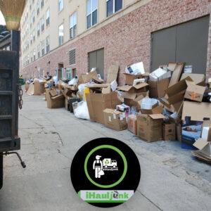 An alleyway overflowing with cardboard boxes and trash, ready for commercial junk removal by IHaul Austin in Austin, TX.