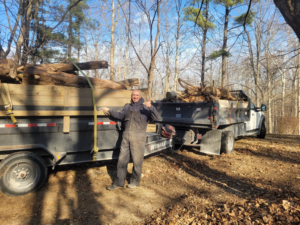 A Schott Services worker giving a thumbs up next to a truck and trailer filled with removed yard junk in Indianapolis, IN.