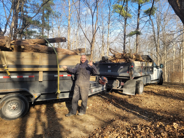 A Schott Services worker giving a thumbs up next to a truck and trailer filled with removed yard junk in Indianapolis, IN.