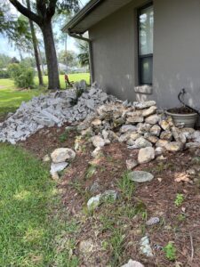 A pile of concrete and rock debris next to a residential building, ready for removal by DUMP 4 U Hauling in Jacksonville, FL