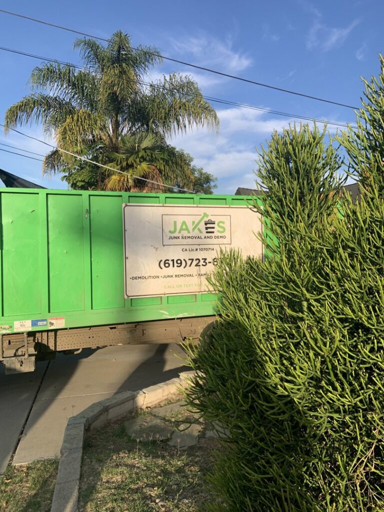 A pile of construction debris, wood, and other junk in a yard, ready for removal by Jake's Junk Removal in San Diego, CA.