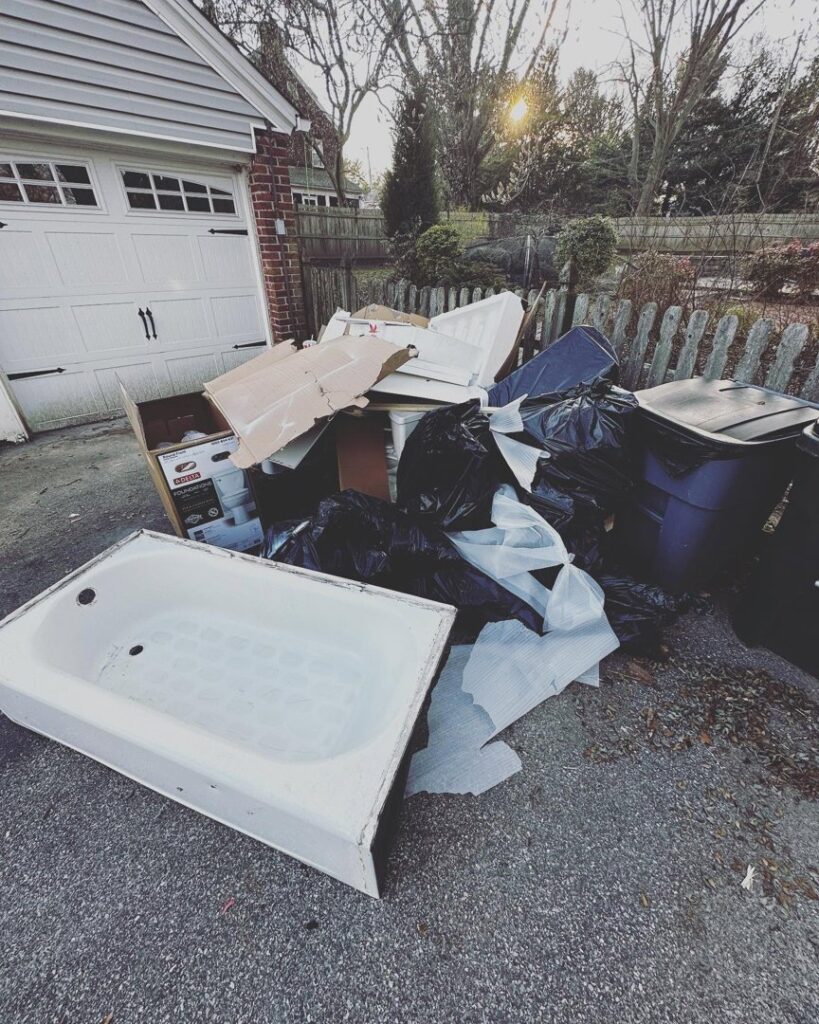 A pile of construction debris and an old bathtub in a driveway for removal by S&M Junk Removal in Philadelphia, PA.