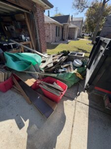 A pile of construction debris and junk next to a dump trailer in a driveway for City to City Junk Removal in Fort Worth, TX.