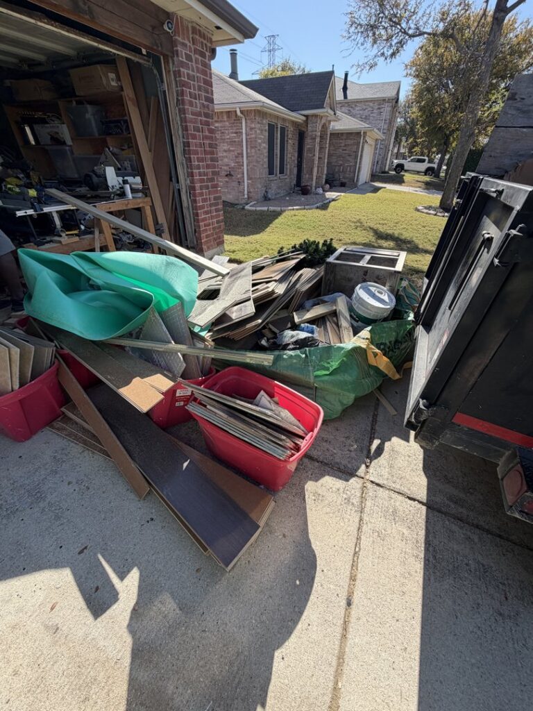 A pile of construction debris and junk next to a dump trailer in a driveway for City to City Junk Removal in Fort Worth, TX.