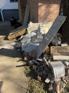 A large pile of construction debris including bricks, concrete, wood, and tiles next to a brick house, ready for removal by HustleTown Junk Removal in Houston, TX.