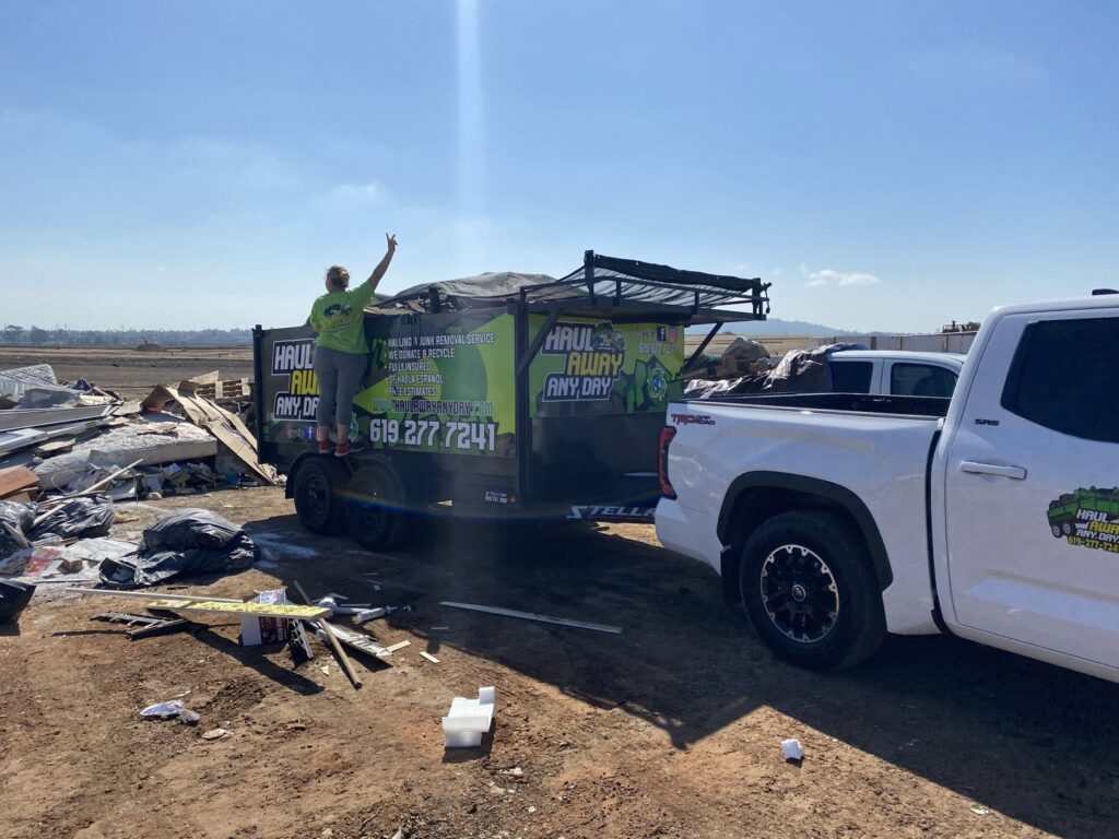 A Haul Away Any Day trailer parked next to a large pile of construction debris for removal in San Diego, CA.