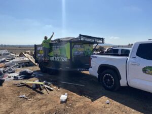 A Haul Away Any Day trailer parked next to a large pile of construction debris for removal in San Diego, CA.