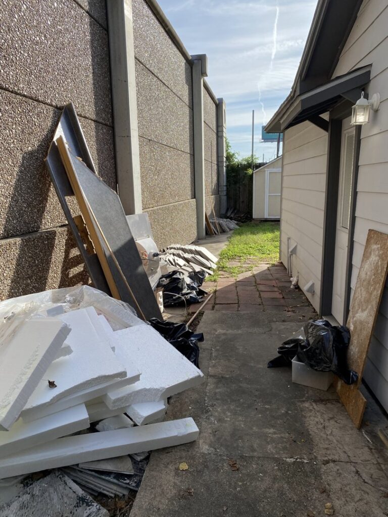 Construction debris, insulation, and trash bags piled in an outdoor area for general junk removal by Get Junk Help in Houston, TX.