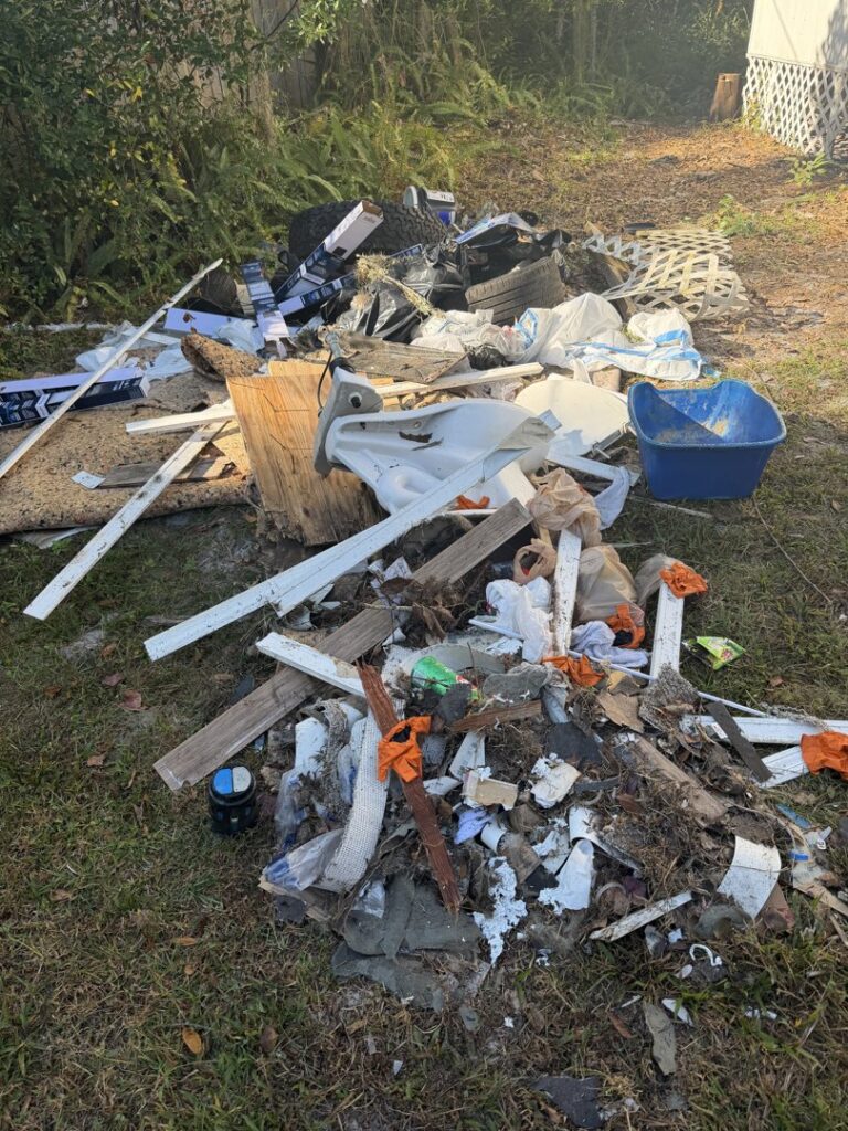 A pile of construction debris, a toilet, and general yard junk awaiting removal by Bring That Junk Removal and Demolition in Jacksonville, FL.