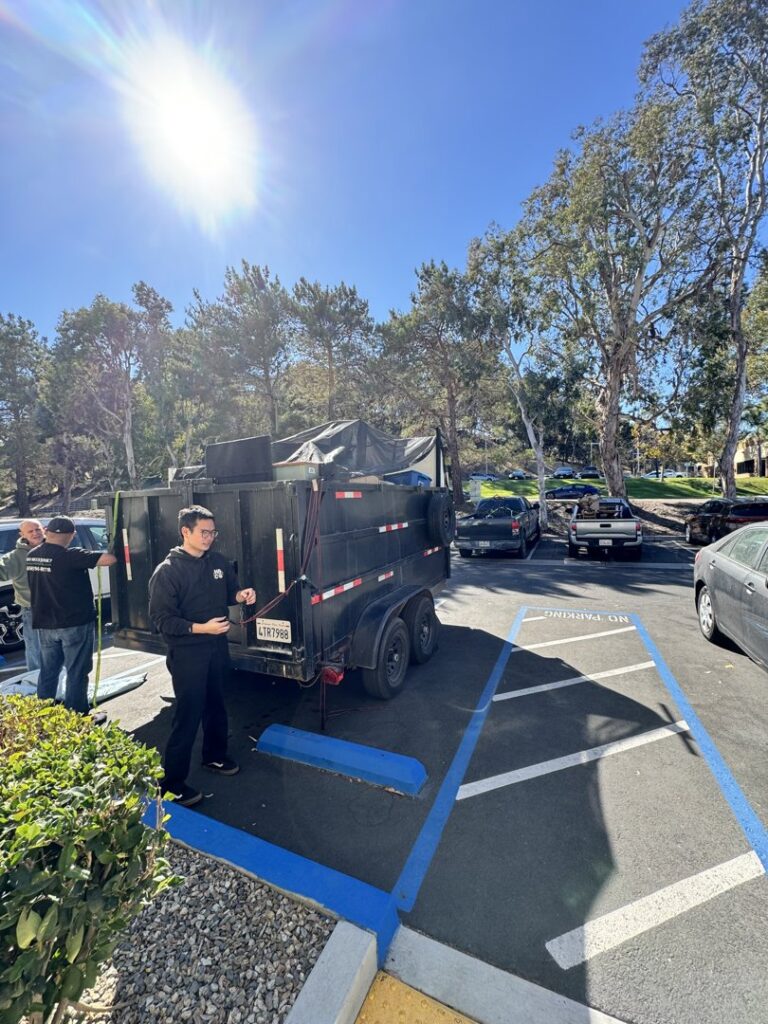 A crew loading a junk removal trailer in a parking lot, showcasing Johan's Junk Removal and Hauling service in San Diego, CA.