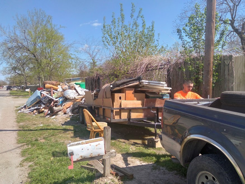 A crew member loading a large pile of residential junk and debris onto a trailer for D & Ds Junk Removal Services in Houston, TX