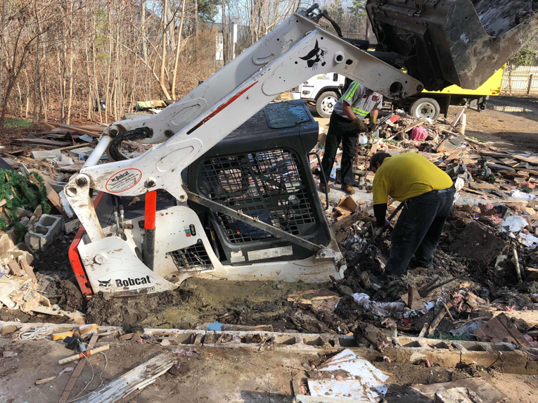 A Junk Doctors of Charlotte crew using a Bobcat skid-steer loader to clear debris from a site in Charlotte, NC.