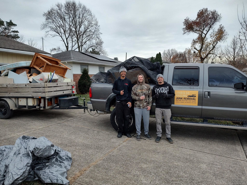 Load & Go Hauling Junk Removal crew with a truck and trailer full of removed junk in a residential driveway in Grove City, OH.