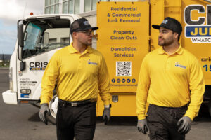 Two Crisan Junk Removal employees in uniform walking in front of their service truck in San Diego, CA.