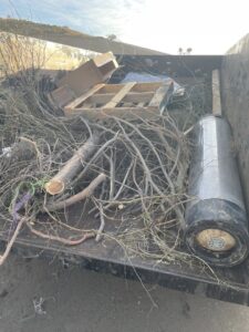 A Cee J Junk Removal LLC trailer loaded with branches, wood, and debris from a cleanout job in Phoenix, AZ.