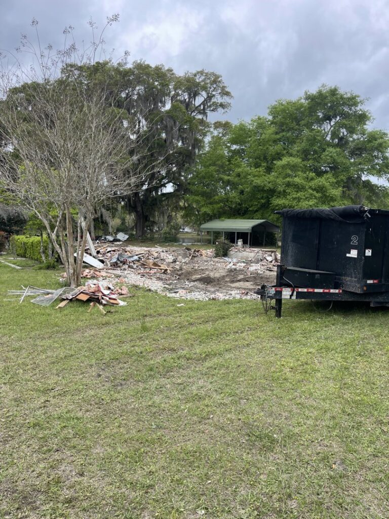 A site with demolition debris and a black roll-off dumpster, showcasing a cleanup job by Jacksonville Hauling & Junk Removal in Jacksonville, FL.