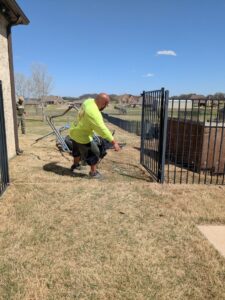 A worker from Herrera Hauling & Junk Removal dismantling a metal fence or structure in Fort Worth, TX.