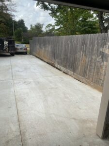 A clean concrete driveway with a junk removal trailer in the background by Right On Time Junk Removal in Houston, TX.